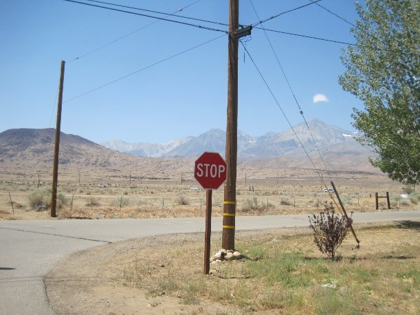 Big Pine Road Intersection which has a stop sign and mountains in the distance