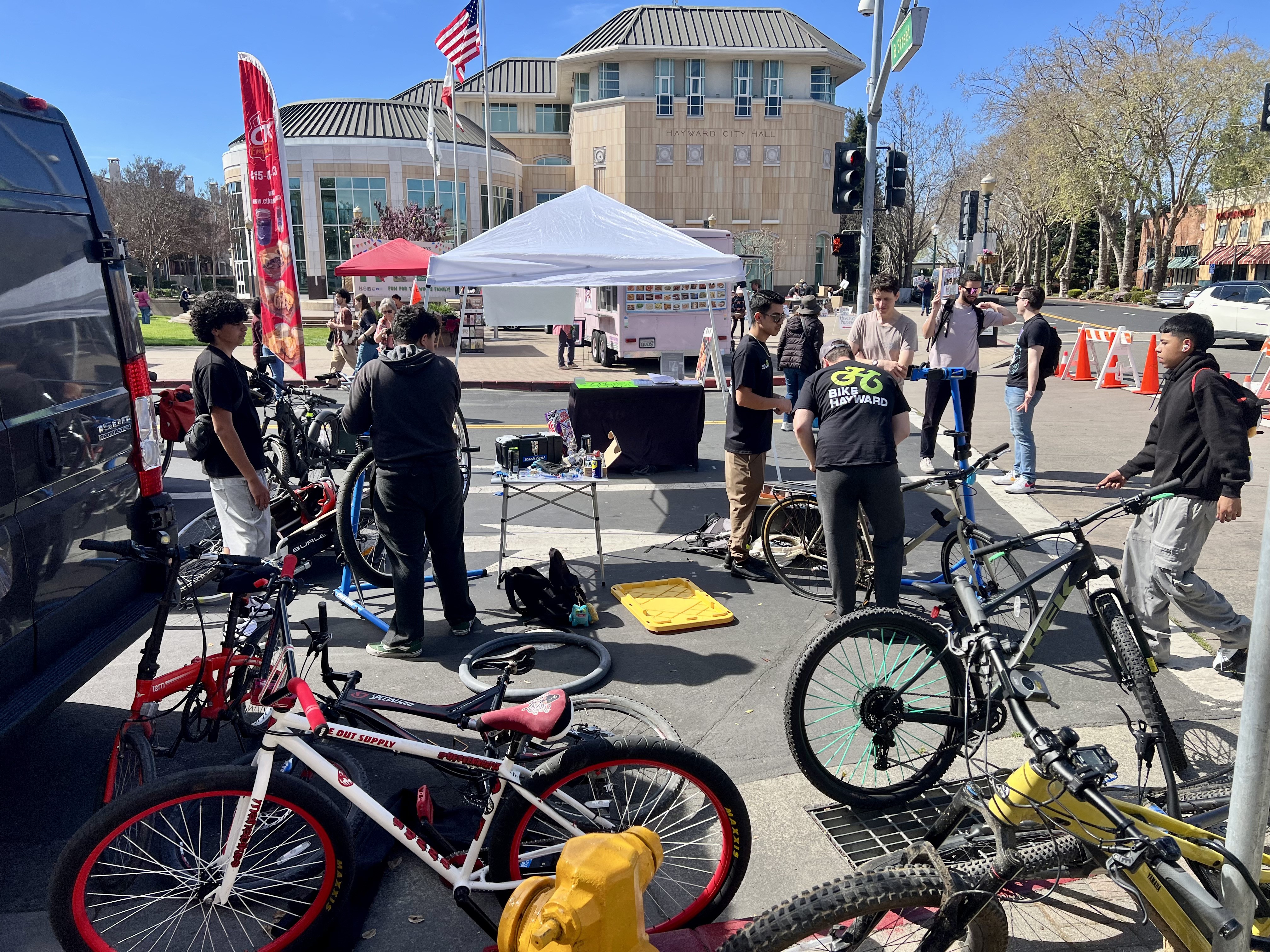 Bikes, students, and volunteers at booth for bike repair event.