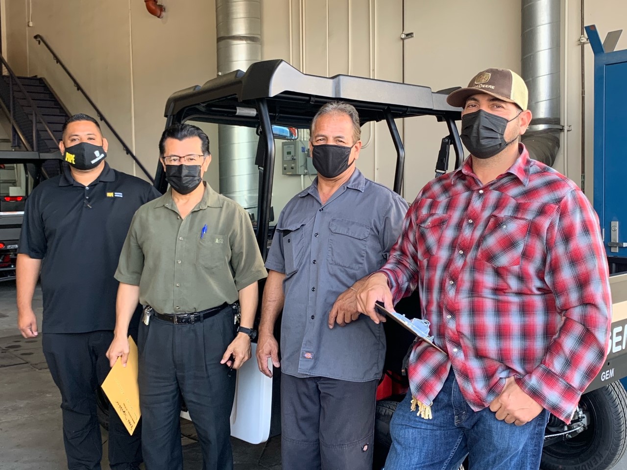 4 El Monte Unified High School Staff pose next to new electric utility carts