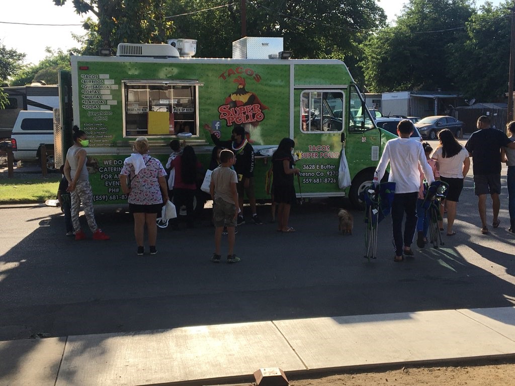 Outdoor community event food truck with several people standing around it