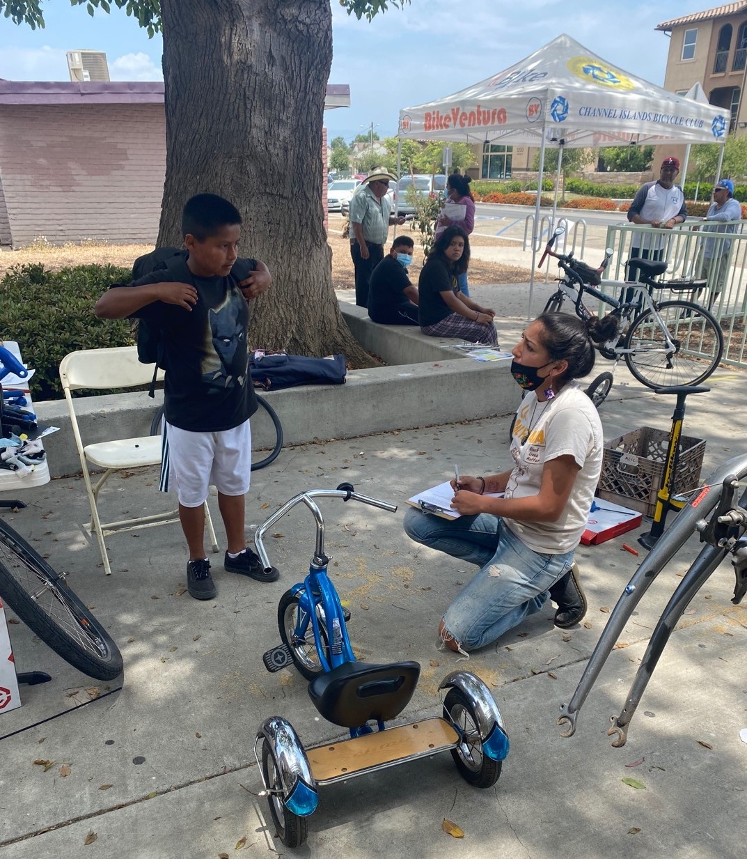 BikeVentura staff kneeling on ground while collecting survey response from a child. 