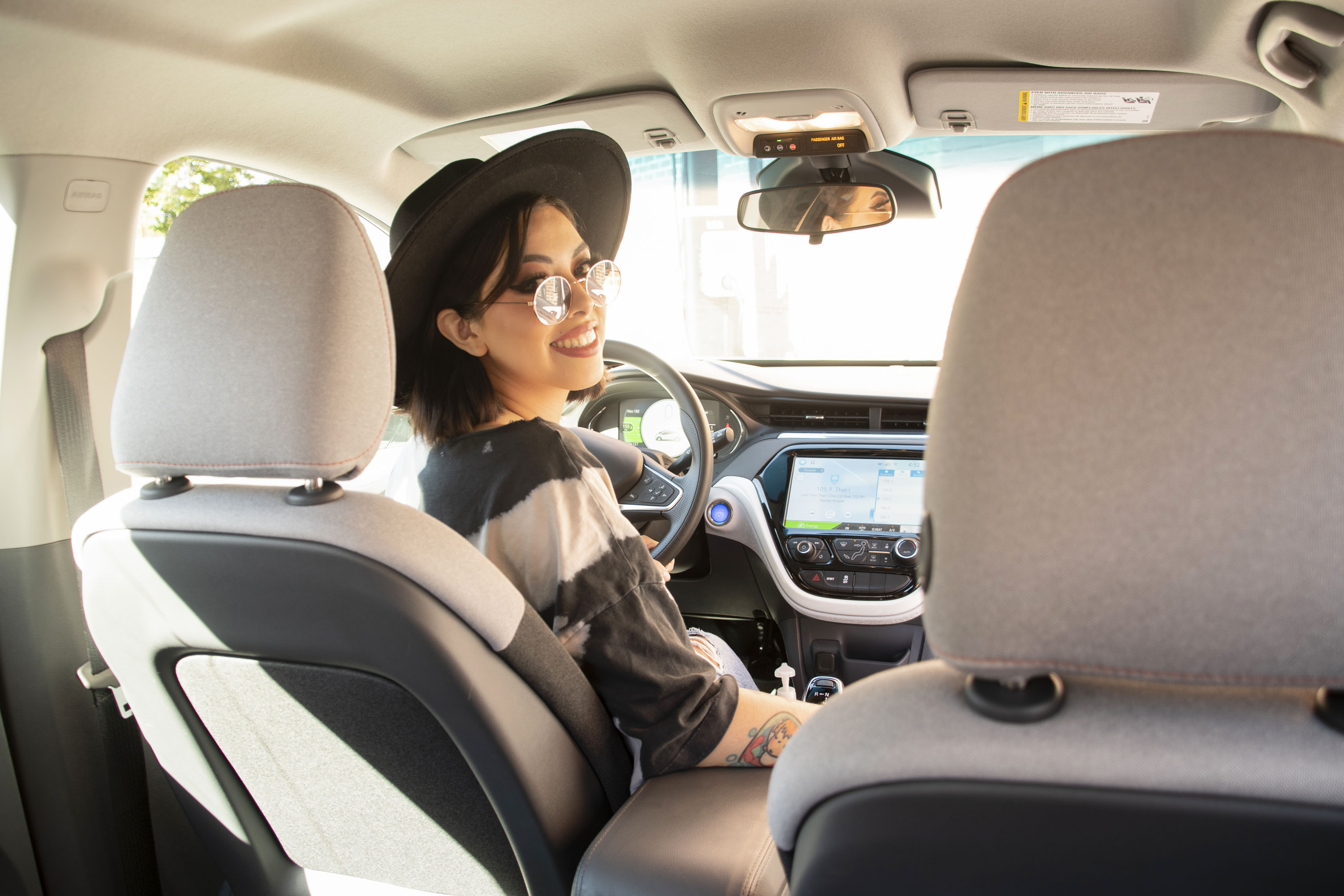 Image from inside a BlueLA Chevy Volt, smiling driver looks toward back seat. 