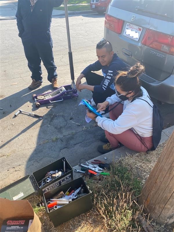 Ecology Action staff sits on curb and helps a resident complete survey