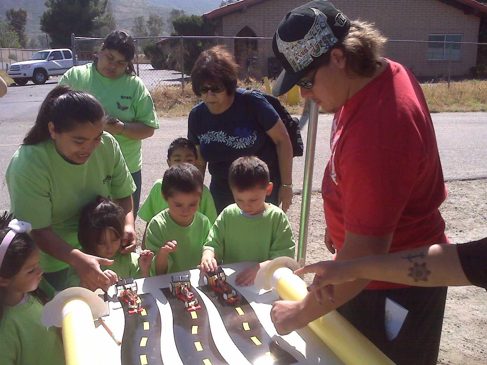 Educational outreach event including an activity with children in which they are playing with vehicle figurines and moving along a printed road