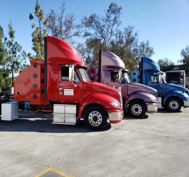 Three Class 8 Fuel Cell Trucks in three different colors: red, purple and blue. 