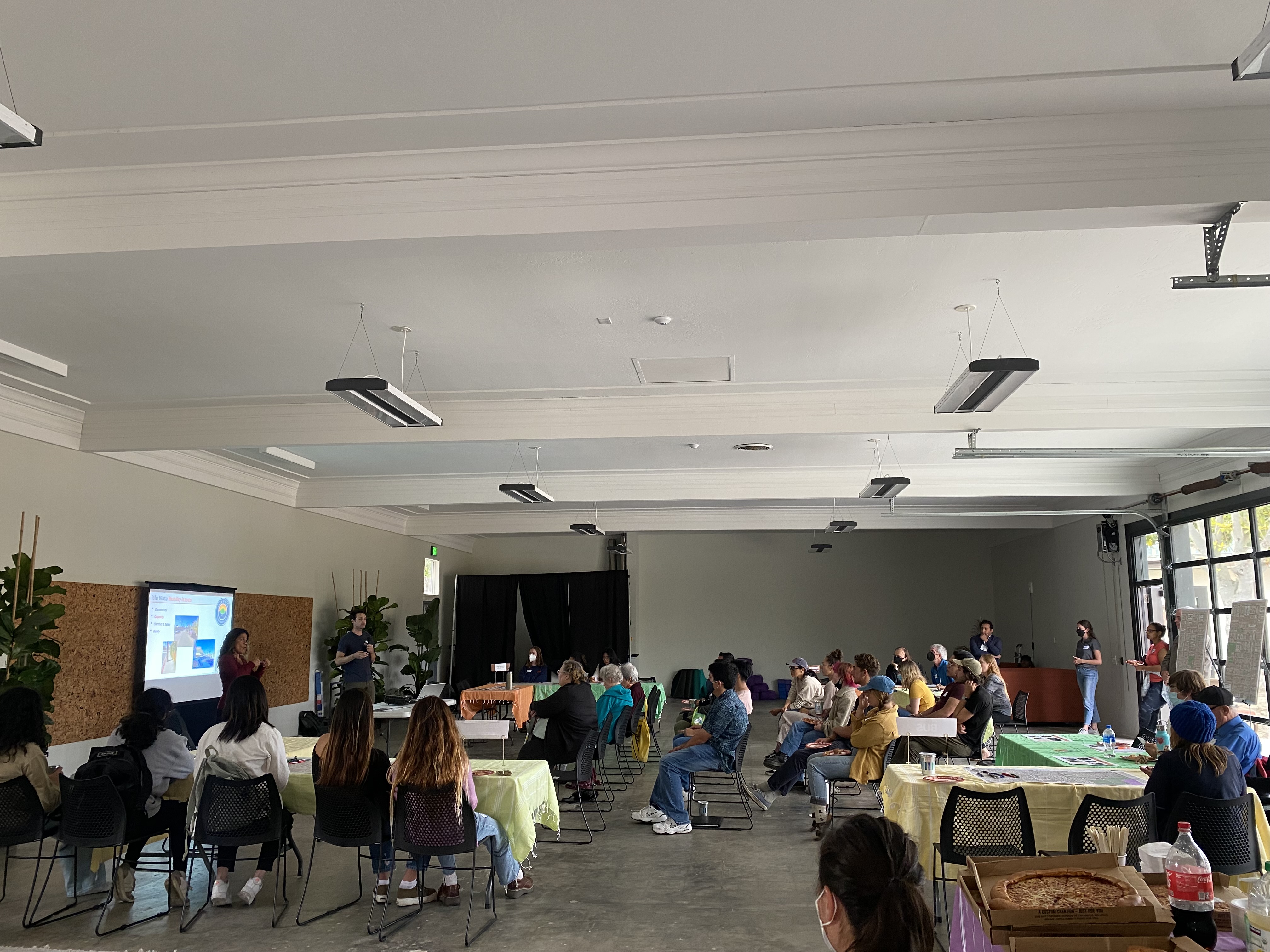 Community workshop with presentation and tables in background 