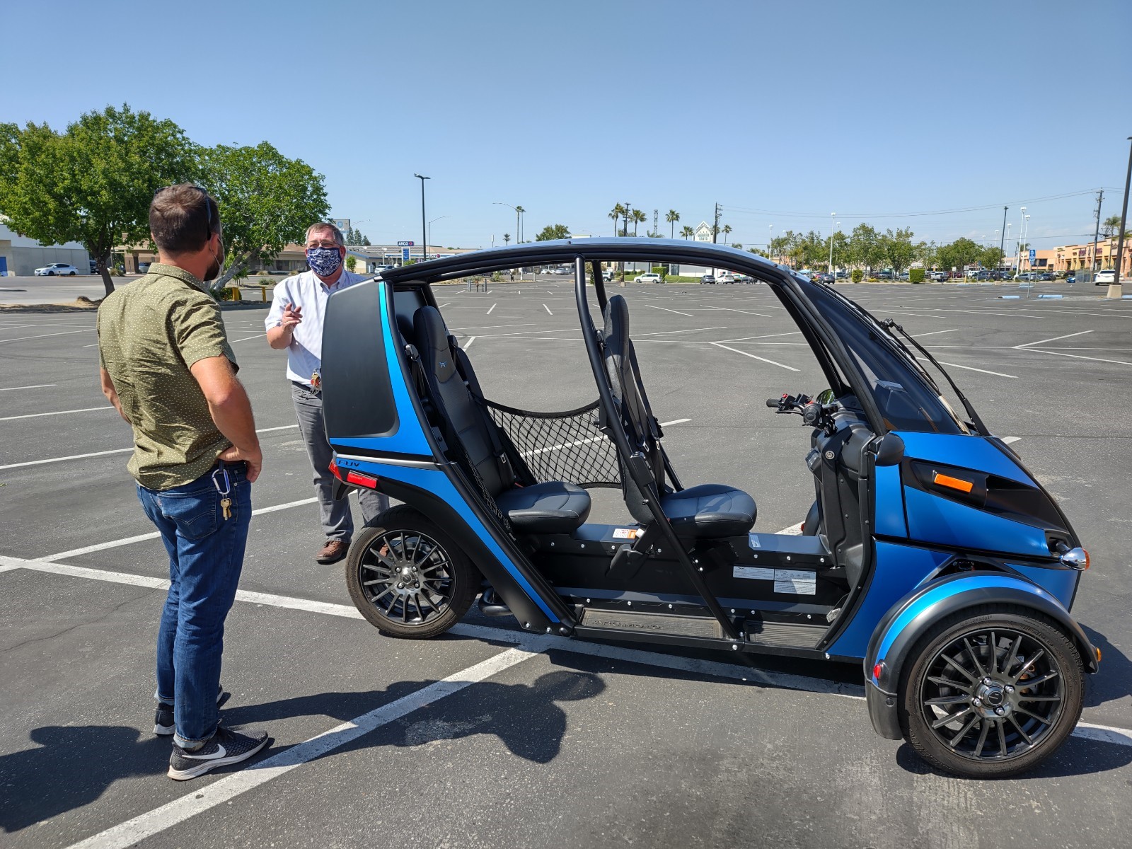 Arcimoto FUV demo at Manchester Center with two participants standing next to blue Arcimoto FUC