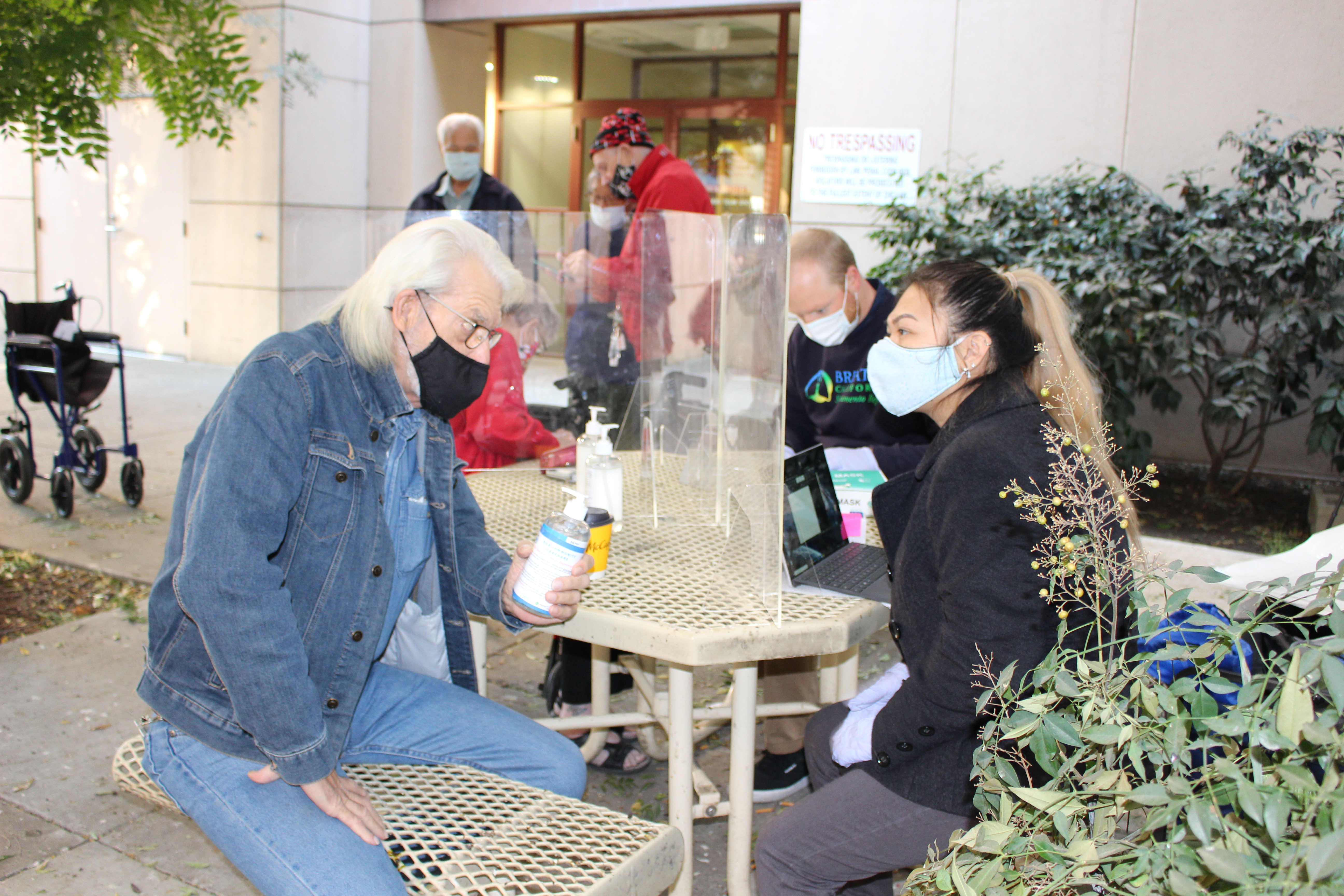 Outreach event and site visit. Carshare staff are speaking with residents at a project site and wearing face protection as a COVID precaution measure.