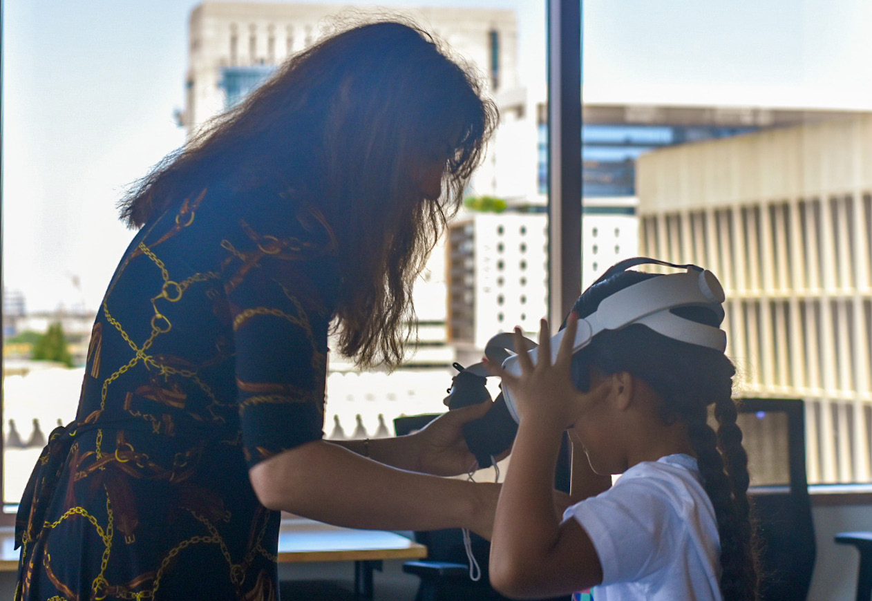 Adult placing virtual reality headset on a child 