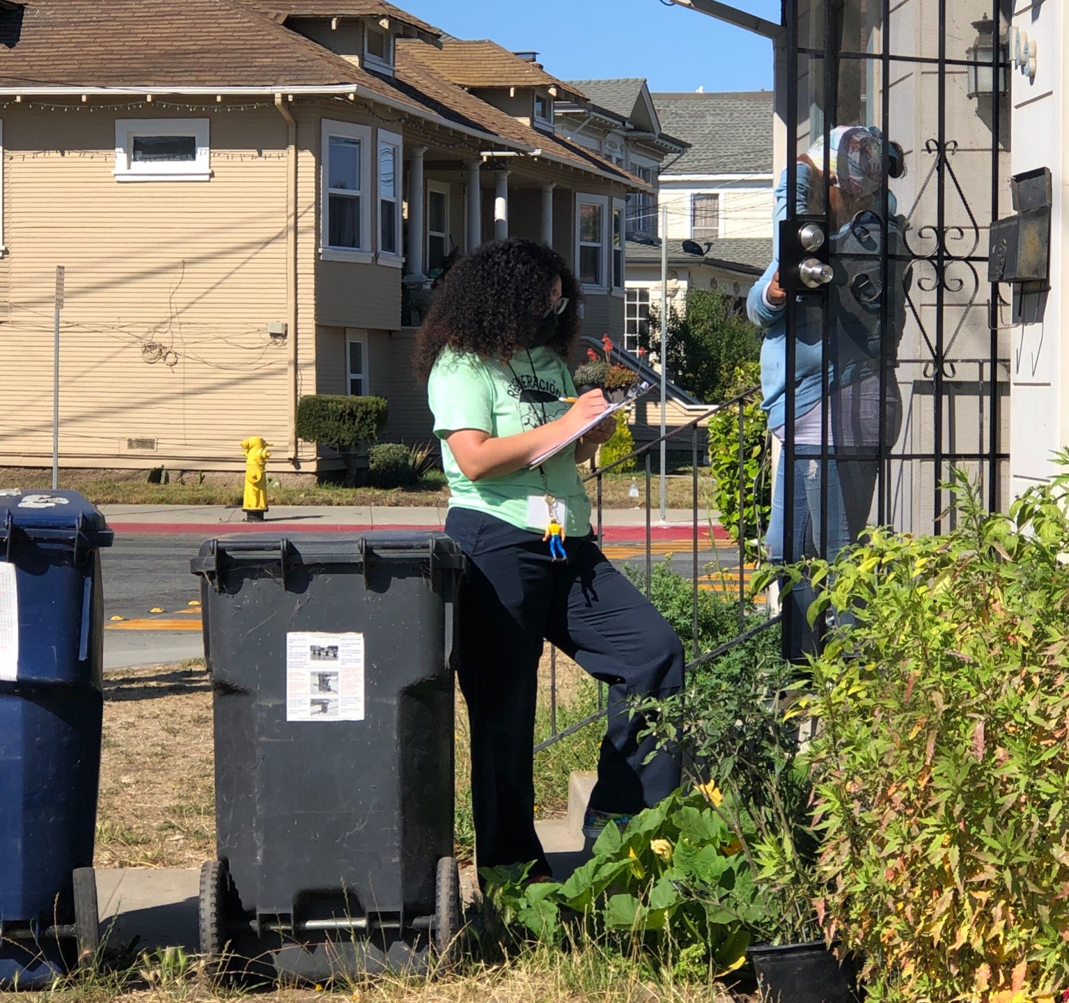 Social Good Fund Project Regeneration survey team member conducting survey at a Watsonville residence and is standing on their porch.