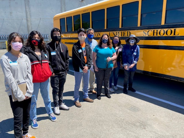 8 SUSD students and staff pose next to new electric school bus