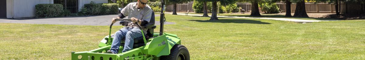 A person using a riding mower on an area of grass.