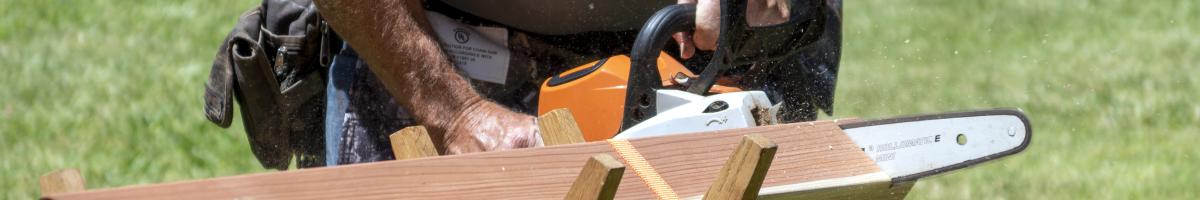 A person using a chainsaw to cut through a piece of wood.