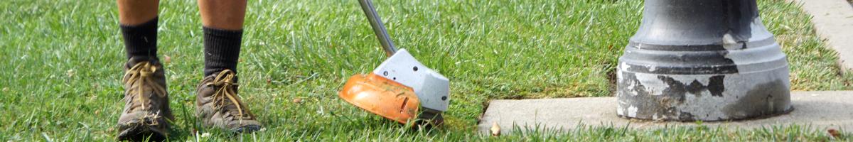 A person using a string trimmer on a grassy area.