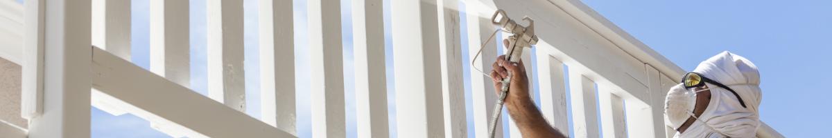 painter spray painting a fence