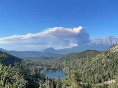 View of a valley with smoke emitted from behind the maoutain.